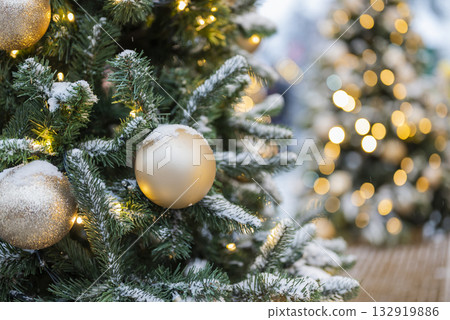 Christmas tree with decorations with toys balls and a garland on a background of bokeh with snow Christmas tree with decorations with toys balls and a garland on a background of bokeh with snow 132919886