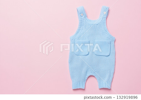 Baby blue knitted onesie on pink background. Fashion newborn clothes. Flat lay top view. Wool kid soft clothing. Infant trendy bodysuit made of organic eco cotton. Children wardrobe. Baby garment 132919896