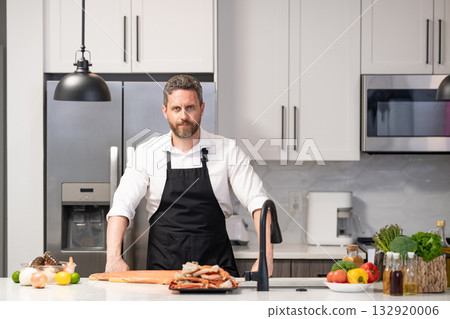 Man cook cooking at kitchen. Hispanic man standing in kitchen preparing sea food. Millennial man cook tasty crab leg. Healthy food diet. Man cook tasty meal. Home menu with seafood food. Copy space Man cook cooking at kitchen. Hispanic man standing in kitchen preparing sea food. Millennial man cook tasty crab leg. Healthy food diet. Man cook tasty meal. Home menu with seafood food. Copy space 132920006