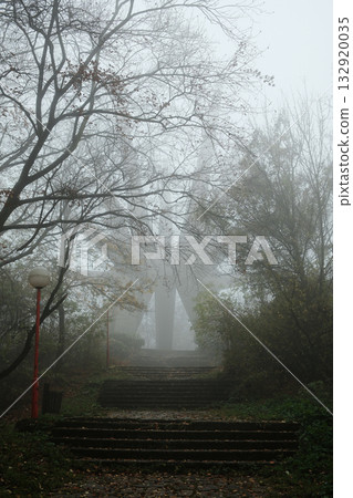 Mysterious view of the Kosmaj Monument rising through dense fog, surrounded by autumn trees and quiet forest atmosphere 132920035