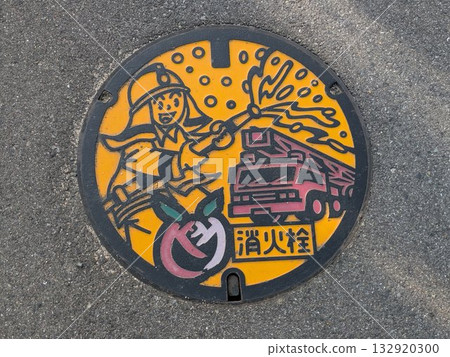 Local manhole cover designed by Fukuyama City, Hiroshima Prefecture, featuring a fire engine, firefighters, and the city's flower, the rose 132920300