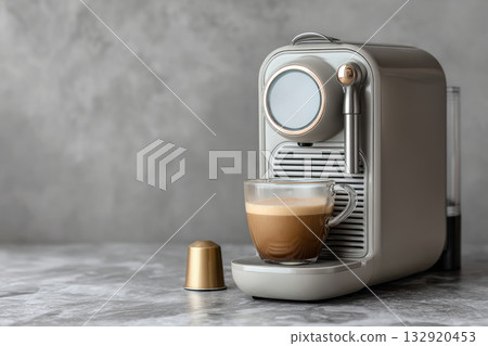 Modern capsule coffee machine brewing fresh coffee into a glass cup on gray marble counter Modern capsule coffee machine brewing fresh coffee into a glass cup on gray marble counter 132920453