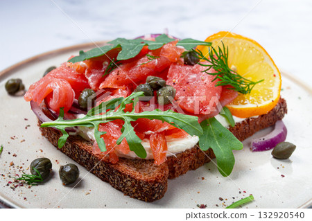 sandwich with freshly smoked salmon, on black bread, with cottage cheese, with herbs and red onions, capers and pieces of citrus fruits, on a marble countertop, breakfast, no people, sandwich with freshly smoked salmon, on black bread, with cottage cheese, with herbs and red onions, capers and pieces of citrus fruits, on a marble countertop, breakfast, no people, 132920540
