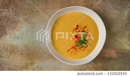 pumpkin cream soup, in a white bowl on a textured background, top view, homemade, no people, rustic style, 132920545