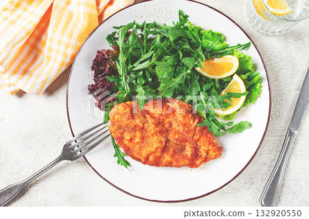 Milanese chicken, Crispy breaded chicken served, with fresh herbs, and lemon wedges, 132920550