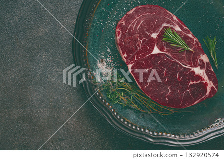 Steak made from fresh beef, with herbs and various spices, on a plate, ready to cook, there are no people 132920574