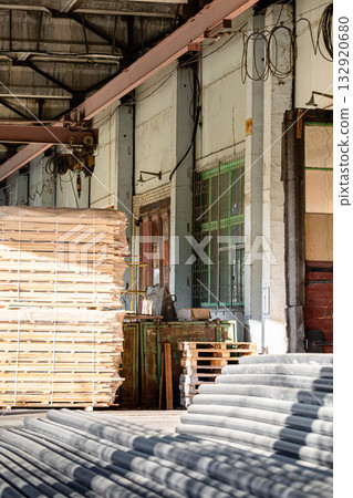 Industrial warehouse interior with stacked wooden pallets and machinery 132920680