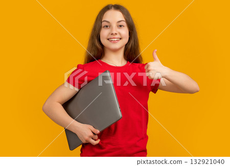 happy girl with laptop on yellow background. thumb up 132921040