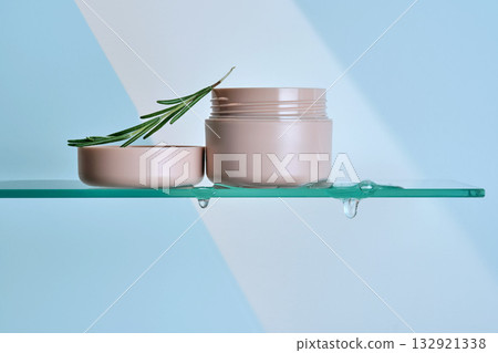 A jar of rosemary cream on the glass shelf of the bathroom. A jar of rosemary cream on the glass shelf of the bathroom. 132921338