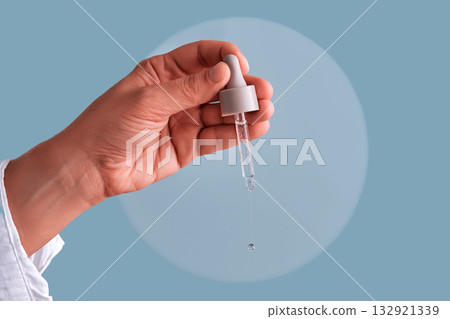 Hand holding dropper dispensing serum skincare liquid 132921339