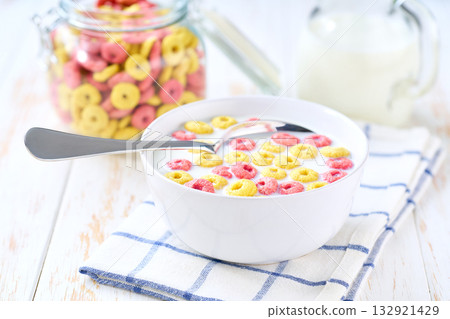 Making a healthy breakfast cereal using corn rings and strawberry rings and milk. 132921429