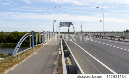 Empty asphalt road on bridge over a river. Blue sky and some clouds over bridge. Transportation concept, cargo transportation 132921584