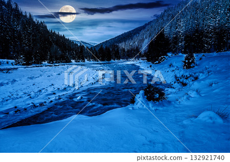 frozen mountain river among spruce forest at night. snow on the ground in full moon light. countryside valley in winter. background for investment or abstract concepts 132921740