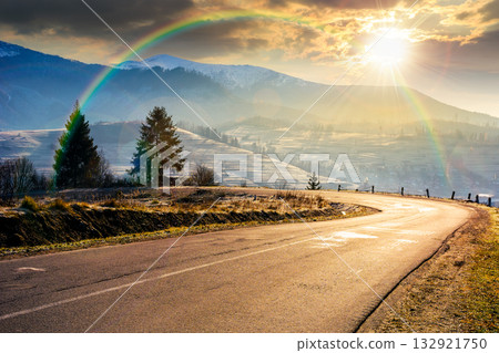 country road in mountains at sunset. beautiful countryside landscape in late autumn. fir trees on the roadside in evening light. scenic view of blue sky with clouds above the distant ridge in snow country road in mountains at sunset. beautiful countryside landscape in late autumn. fir trees on the roadside in evening light. scenic view of blue sky with clouds above the distant ridge in snow 132921750