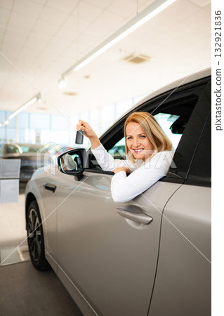 Smiling woman holding car key sitting in new car 132921836