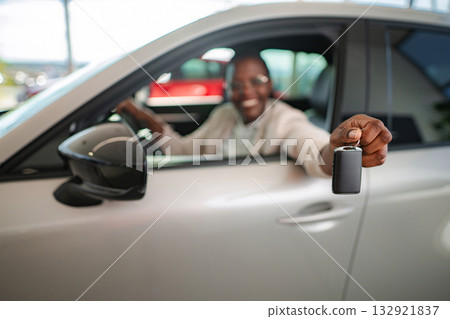 Happy man holding new car key at dealership 132921837