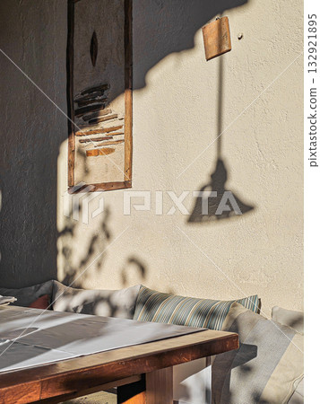 Close-up of wall with shadows from hanging lamp, table partially visible in foreground. 132921895