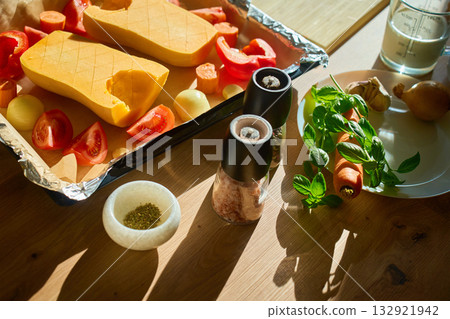Fresh pumpkin and vegetables prepared for roasting on kitchen table 132921942