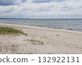 Baltic Sea sandy beach with dune grass and calm waves under a moody cloudy sky 132922131