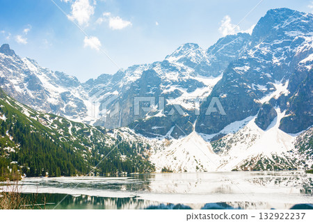 landscape with lake in tatra mountains of poland in spring. snow covered rocky peaks. outdoor adventure and vacation season on morskie oko landscape with lake in tatra mountains of poland in spring. snow covered rocky peaks. outdoor adventure and vacation season on morskie oko 132922237