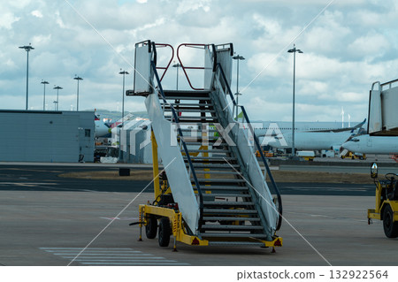 Airport boarding stairs on tarmac with airplanes in background Airport boarding stairs on tarmac with airplanes in background 132922564