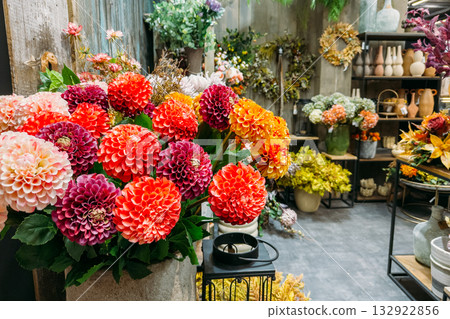 Brightly colored artificial dahlia flowers in a rustic floral shop. Faux botanicals, sustainable retail decor, flower styling, handmade aesthetics Brightly colored artificial dahlia flowers in a rustic floral shop. Faux botanicals, sustainable retail decor, flower styling, handmade aesthetics 132922856