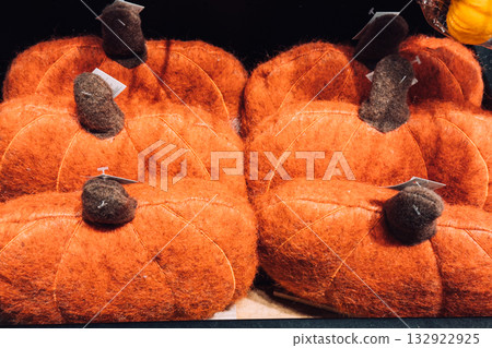 Cluster of soft felt pumpkins in orange with brown stems arranged for seasonal retail display. Non-toxic decor, handmade seasonal styling, plastic-free holiday inspiration, sustainable fabric craft 132922925