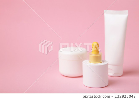 Set of various cosmetic products in blank packaging, creams in jars, serum in bottle on pink background. Space for text Set of various cosmetic products in blank packaging, creams in jars, serum in bottle on pink background. Space for text 132923042