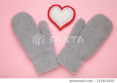 Warm grey mittens with heart on pink background. Warm grey mittens with heart on pink background. 132923050