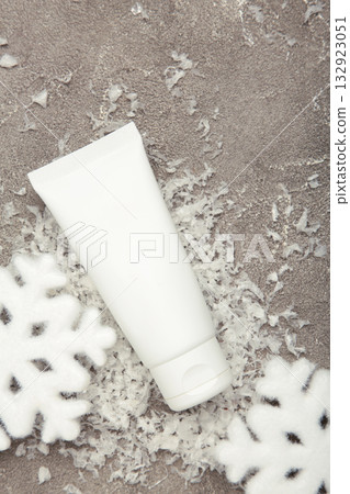 Winter skin care concept. Cosmetic moisturizer cream and snowflakes on grey background. Vertical photo 132923051