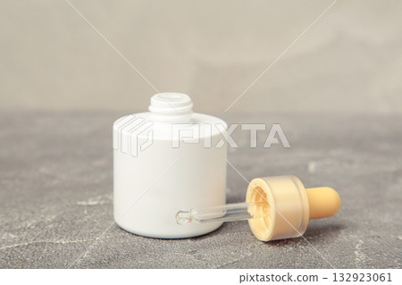 Minimalist white cosmetic dropper bottle on grey background. Elegant mockup for skincare, serum, or beauty branding presentations. 132923061