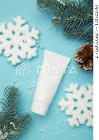 Winter skin care concept. Cosmetic moisturizer cream and snowflakes on blue background. Vertical photo Winter skin care concept. Cosmetic moisturizer cream and snowflakes on blue background. Vertical photo 132923063