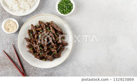 Asian-style beef stir fry with teriyaki sause, sesame seeds, green onions and rice. Top view, copy space. Asian-style beef stir fry with teriyaki sause, sesame seeds, green onions and rice. Top view, copy space. 132923869