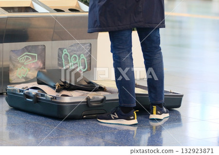 Foreign tourists packing their suitcases in the airport departure lobby Foreign tourists packing their suitcases in the airport departure lobby 132923871