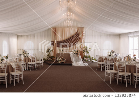 Wedding banquet hall with elegant stage and round tables decorated in beige and white tones Wedding banquet hall with elegant stage and round tables decorated in beige and white tones 132923874