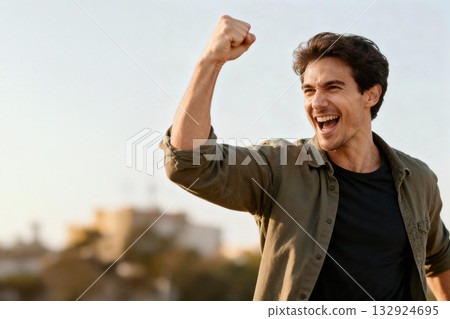 一個年輕人興奮地揮舞著拳頭,奔向光明的未來。 一個年輕人興奮地揮舞著拳頭,奔向光明的未來。 132924695