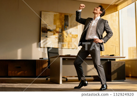 一位商人得意洋洋地站在明亮的辦公室。 一位商人得意洋洋地站在明亮的辦公室。 132924920