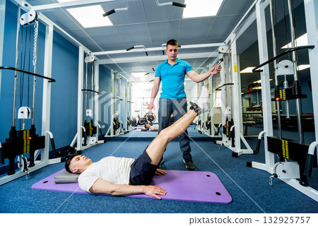 Rehabilitation therapy. Young man doing exercises on mat Rehabilitation therapy. Young man doing exercises on mat 132925757