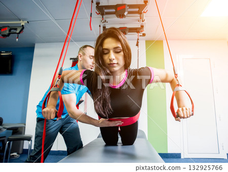 Physiotherapy. Suspension training therapy. Young woman doing fitness traction Physiotherapy. Suspension training therapy. Young woman doing fitness traction 132925766
