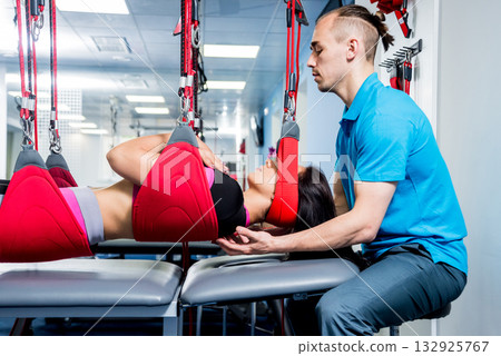 Physiotherapy. Suspension training therapy. Young woman doing fitness traction Physiotherapy. Suspension training therapy. Young woman doing fitness traction 132925767
