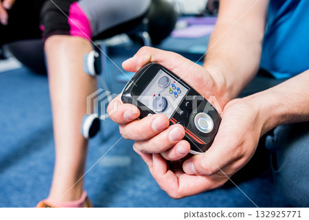 Physical therapist install electrostimulator on the muscles of the legs. Physical therapist install electrostimulator on the muscles of the legs. 132925771