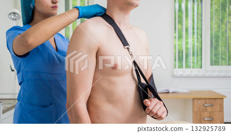 Nurse putting a sling on patients arm that is broken. Injury 132925789