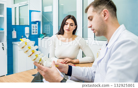 Orthopedist showing spine model to patient in hospital 132925801