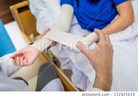 Male doctor bandaging hand of female patients. 132925819