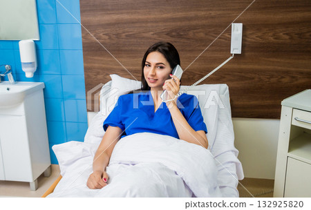 Patient talking on the phone in hospital bed. Young caucasian woman. 132925820