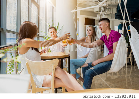 Cheerful friends in the pub. Drinking beer, talking, having fun. 132925911