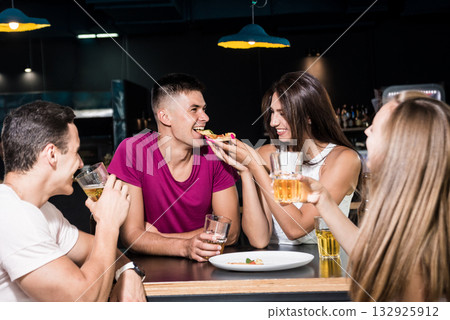 Cheerful friends in the pub. Drinking beer, eating pizza, talking, having fun. Cheerful friends in the pub. Drinking beer, eating pizza, talking, having fun. 132925912