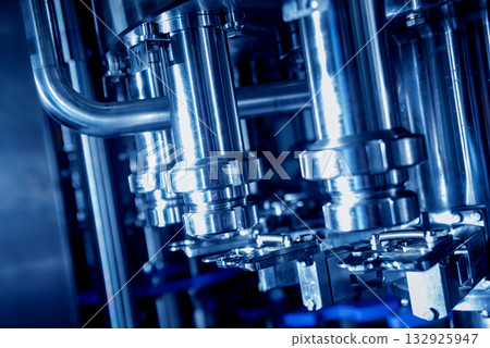 Automatic filling machine pours water into plastic PET bottles. 132925947