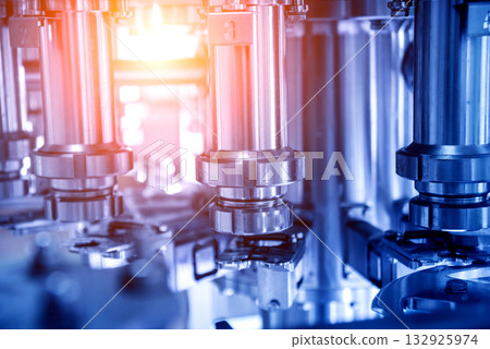 Automatic filling machine pours water into plastic PET bottles. 132925974