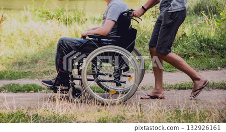 Disabled man resting in a campsite with friends. Wheelchair in the forest Disabled man resting in a campsite with friends. Wheelchair in the forest 132926161
